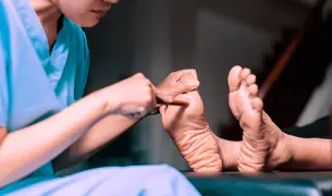 אחות בודקת את הרגליים של מטופל סוכרת