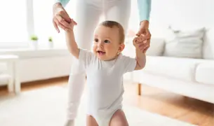 תינוקת הולכת בעזרת הידיים של אמא צעדים ראשונים