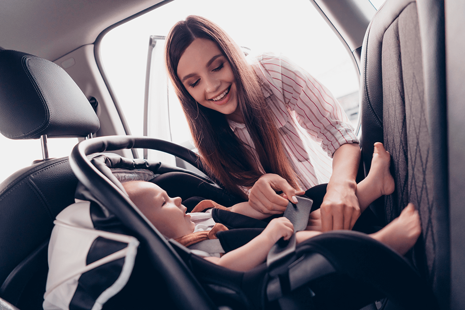 Mother belts the baby in a booster seat