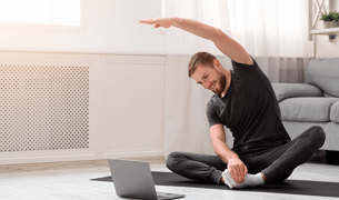 גבר מול מחשב עושה ספורט בבית