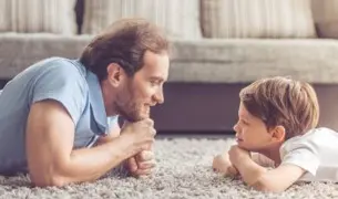 אבא ובן שוכבים על שטיח ומסתכלים זה על זה